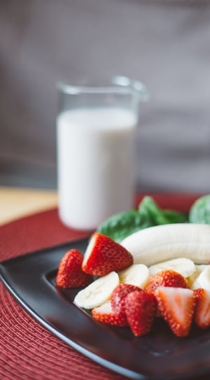 selective focus photo of ripe strawberries and banana on top of black plate thumbnail
