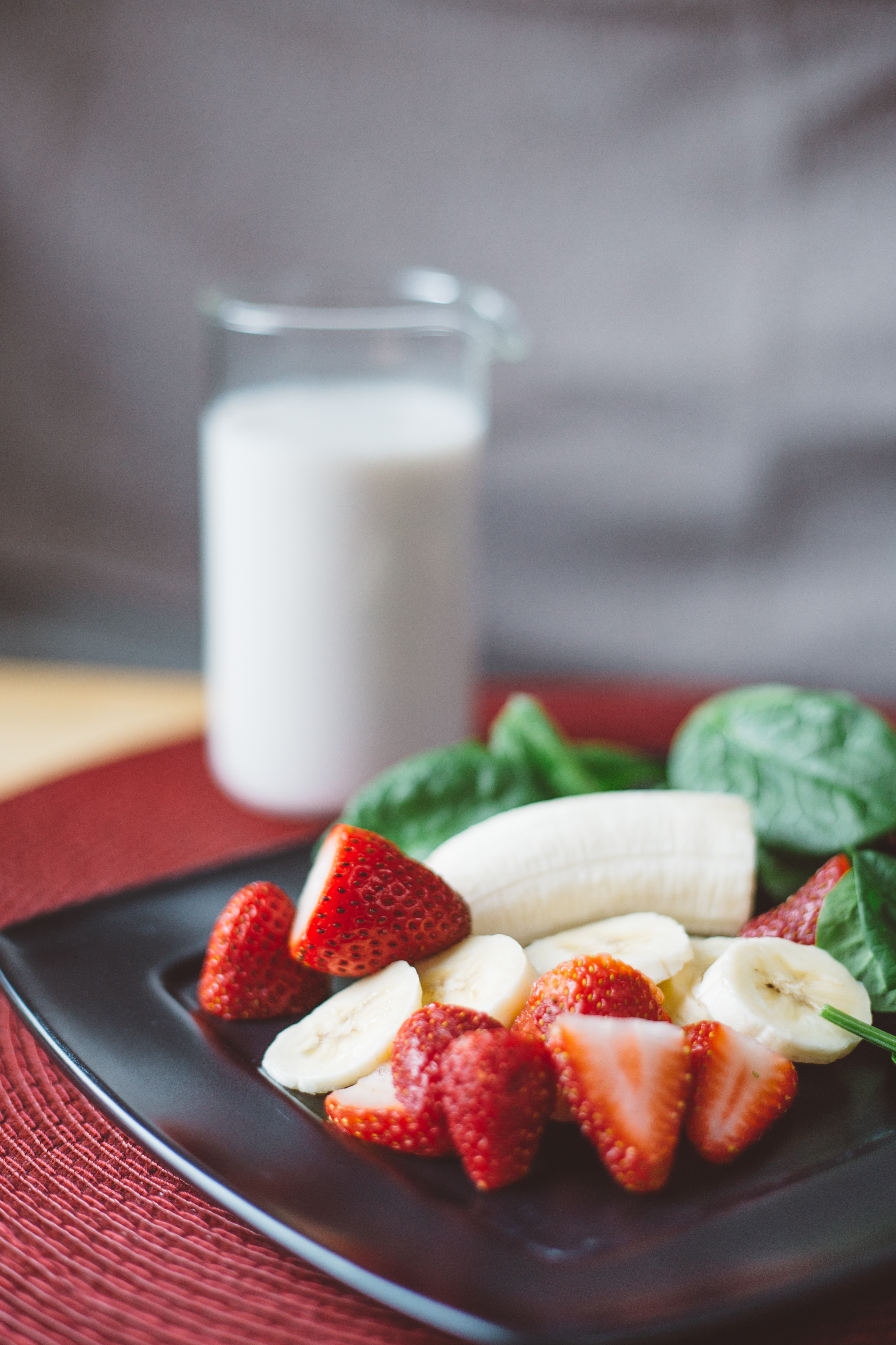 selective focus photo of ripe strawberries and banana on top of black plate