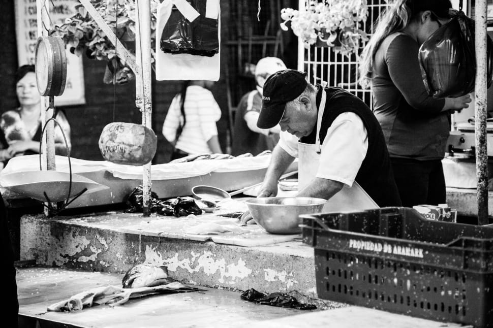 man selling fish in wet market grayscale photo preview