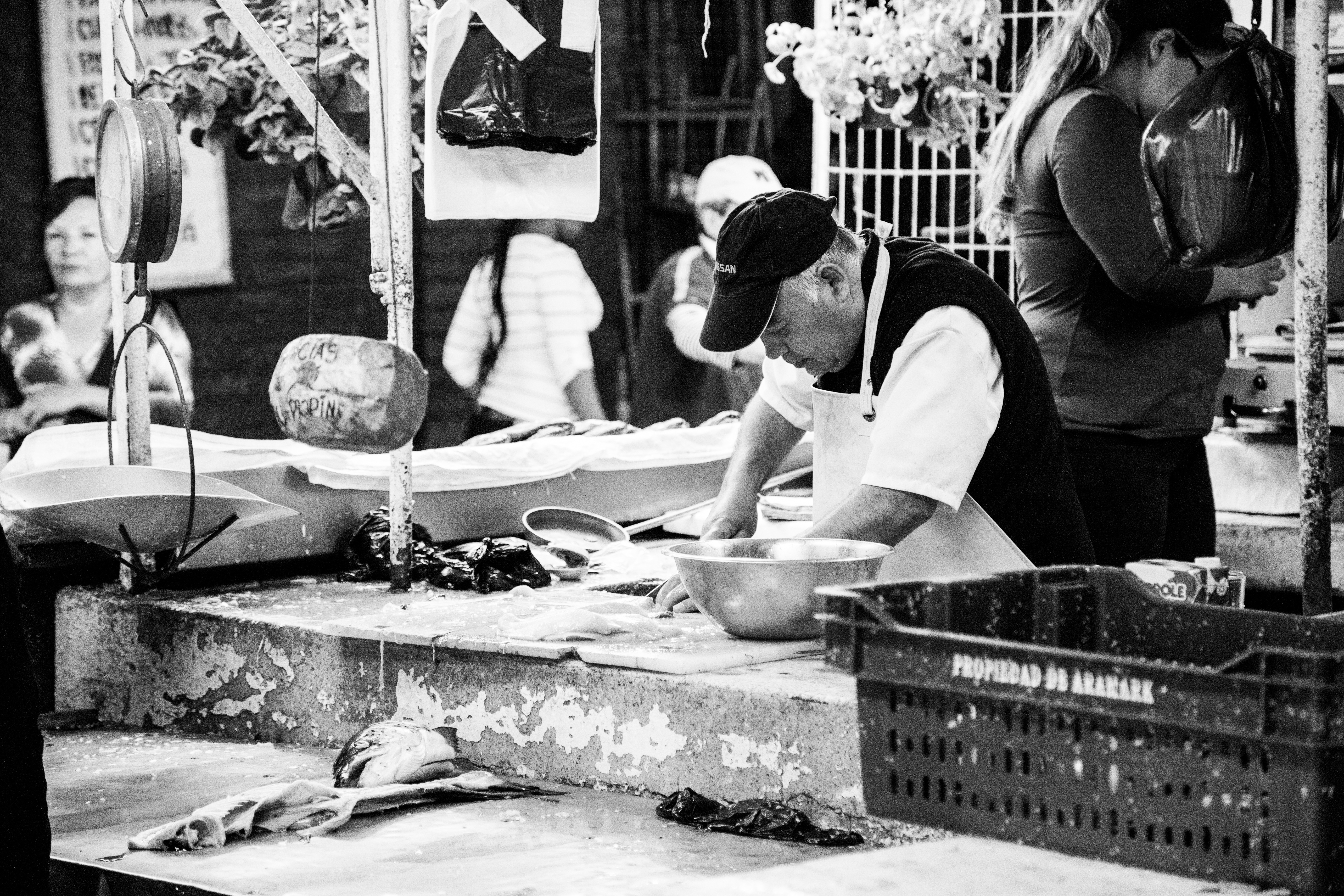man selling fish in wet market grayscale photo