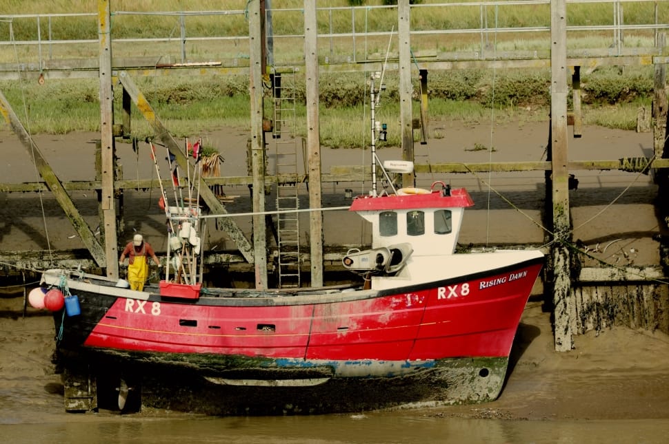 man on red fishing boat by the dock preview