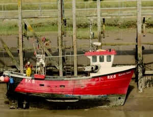 man on red fishing boat by the dock thumbnail