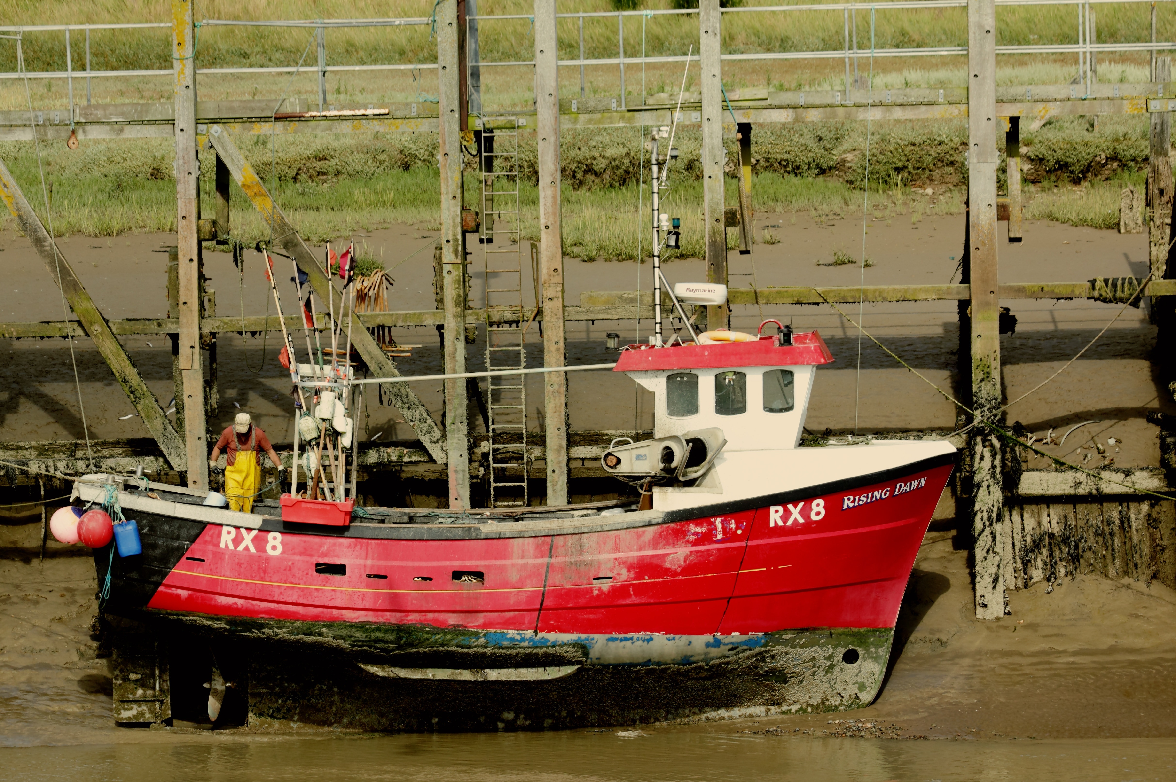 man on red fishing boat by the dock