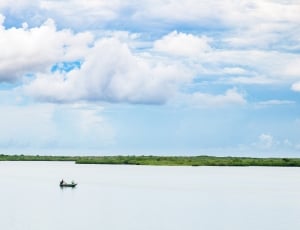 boat in the body of water near trees under the cumulus cloud thumbnail