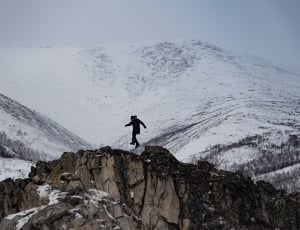 man in black suit jumping above mountain during daytime thumbnail