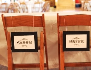 2 brown wooden chairs with groom and bride signage thumbnail