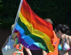 woman in red and blue floral dress holding lgbt flag thumbnail