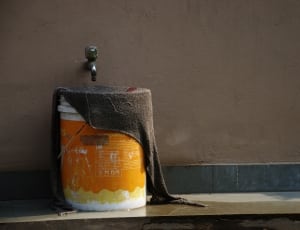 white and orange plastic container with brown textile top under chrome faucet thumbnail
