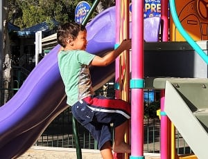 child climbing outdoor slides during daytime photo thumbnail