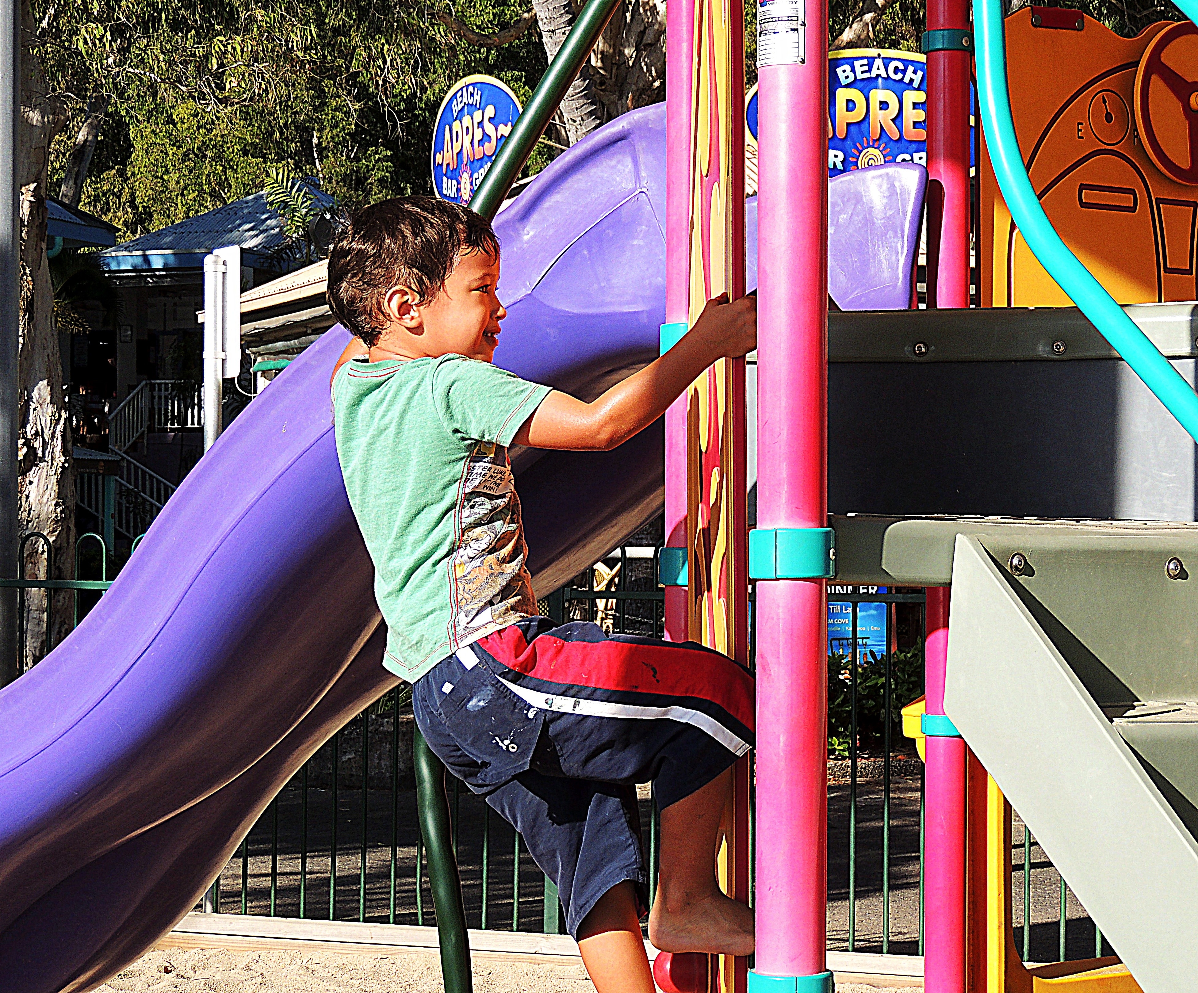 child climbing outdoor slides during daytime photo