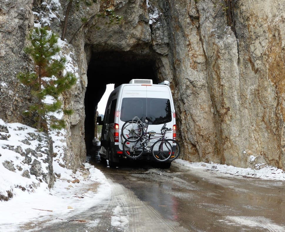 white van with bicycle on tail end approaching cave preview