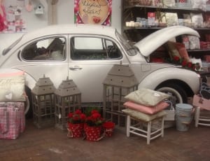 white Volkswagen Beetle car field with assorted item lot thumbnail
