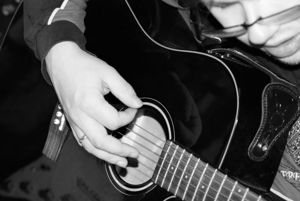 grayscale photo of person holding acoustic guiyar preview