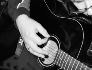 grayscale photo of person holding acoustic guiyar thumbnail