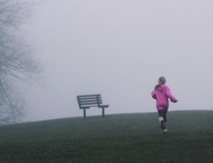 female wearing pink jacket running toward green grass thumbnail