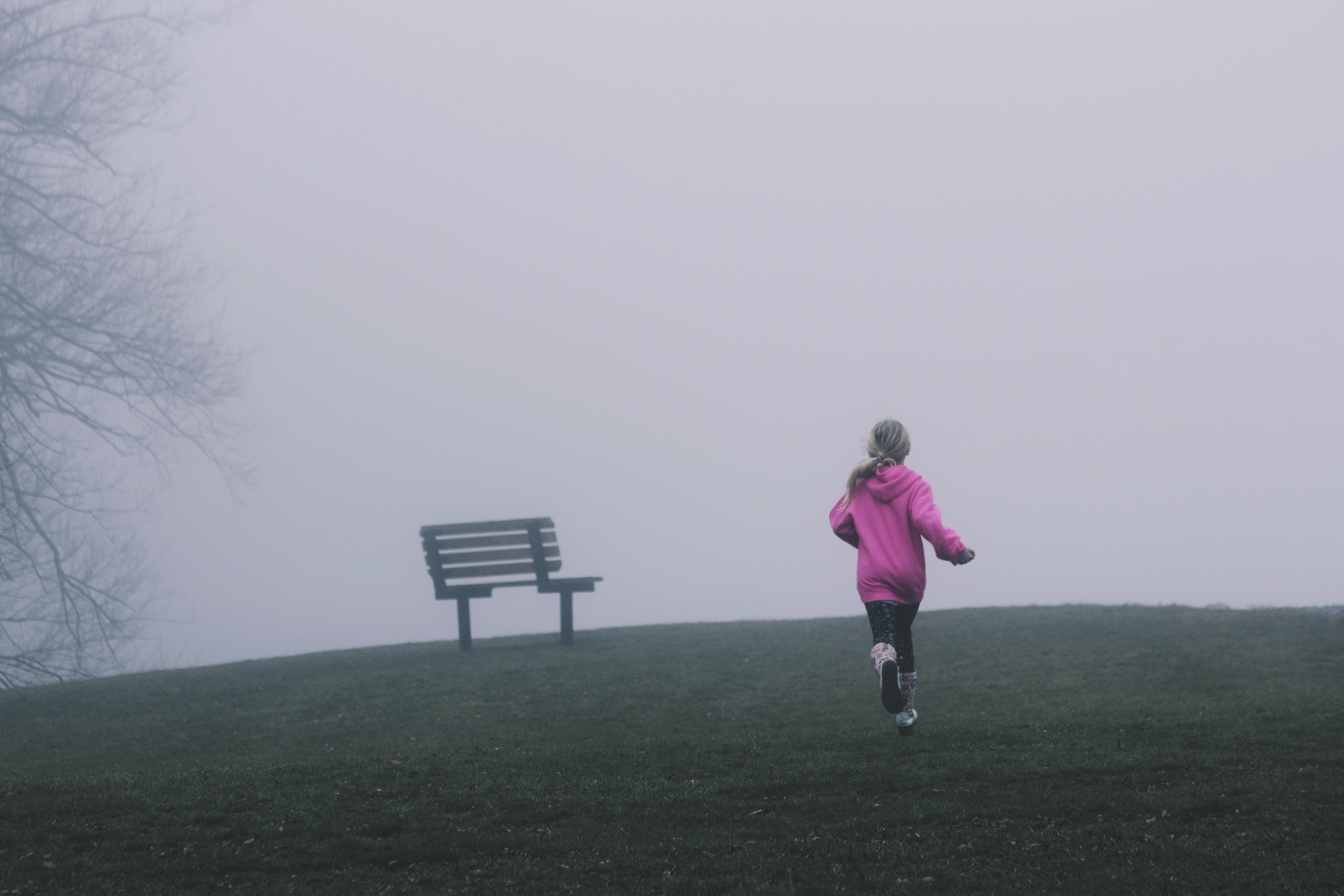 female wearing pink jacket running toward green grass