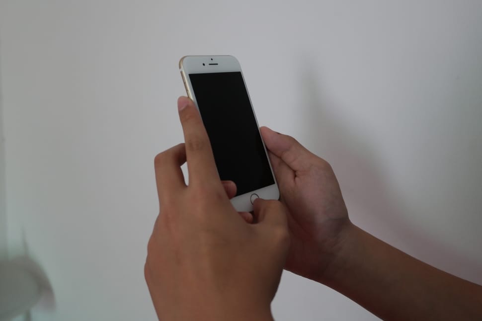 person holding iphone 6 beside white painted wall preview