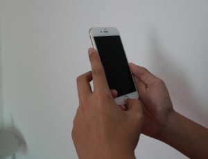 person holding iphone 6 beside white painted wall thumbnail