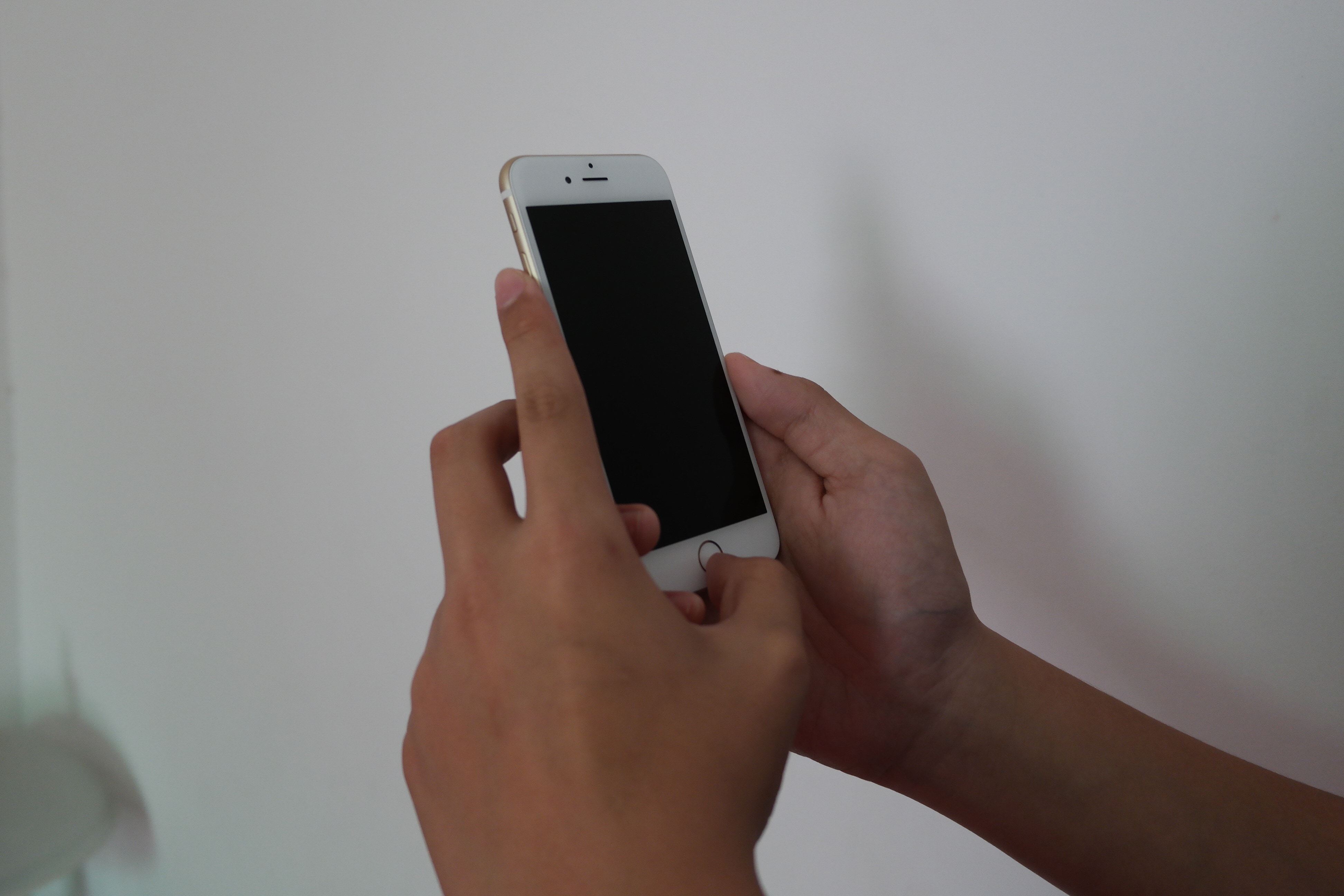 person holding iphone 6 beside white painted wall