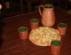 brown ceramic pitcher and drinking glasses and pizza thumbnail