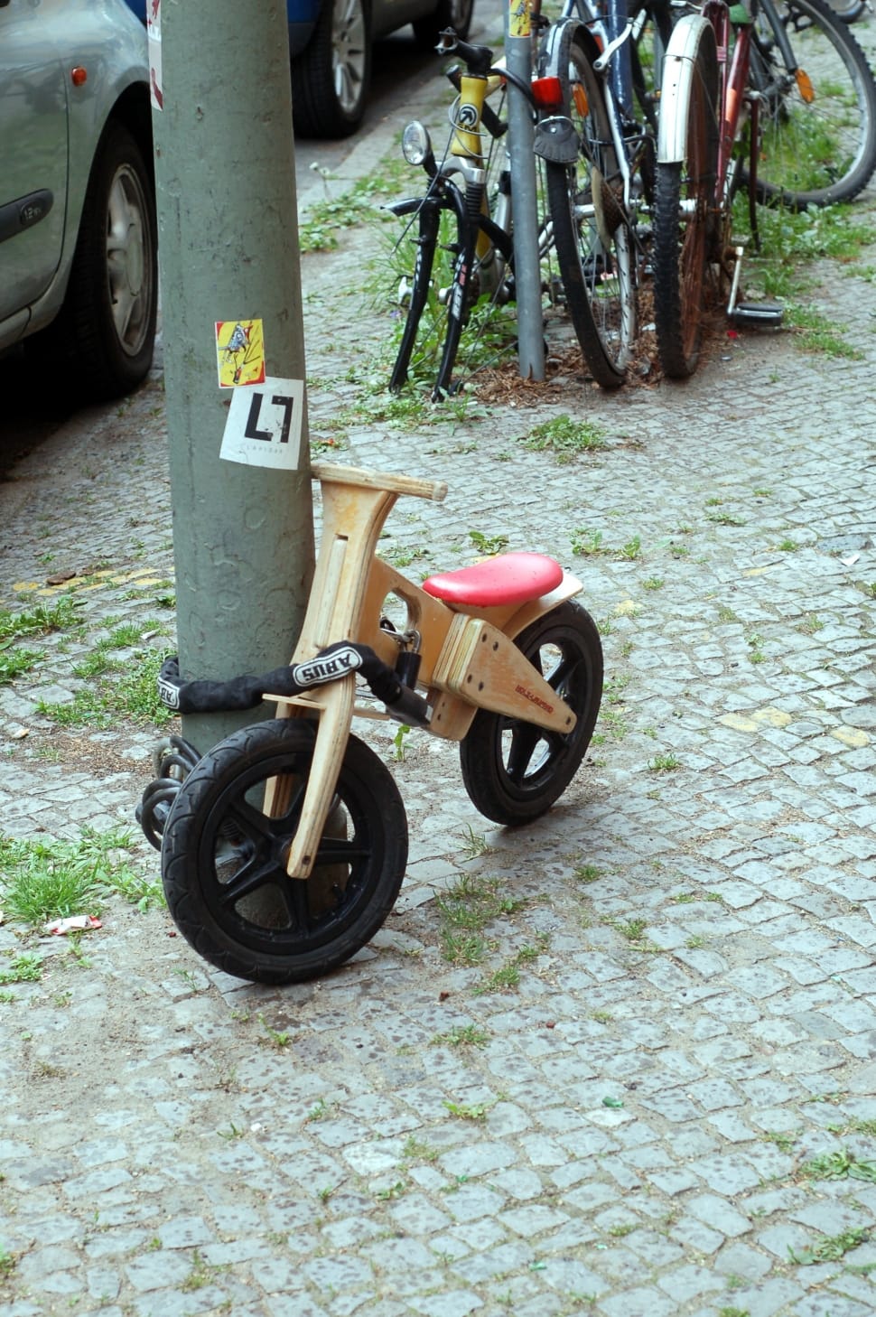 brown balance bike leaning on gray pole preview