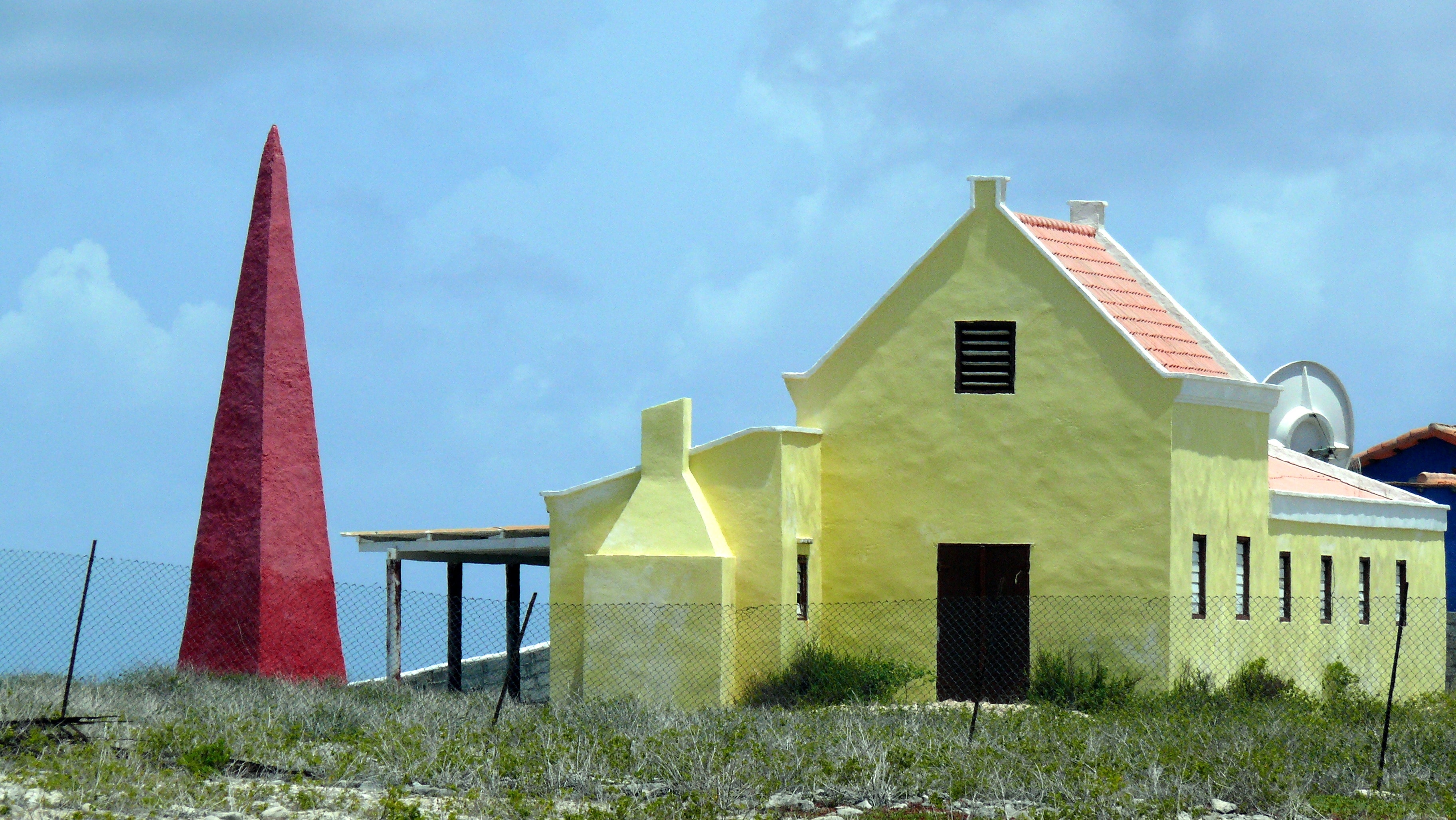yellow concrete house beside red tower