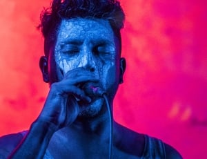 man in blue body paint holding microphone thumbnail