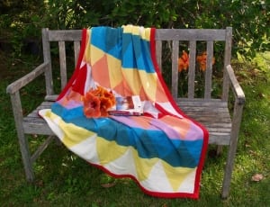 gray wooden bench; red yellow and blue textile thumbnail