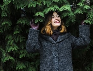 woman wearing gray and black button up coat under green leaf trees thumbnail