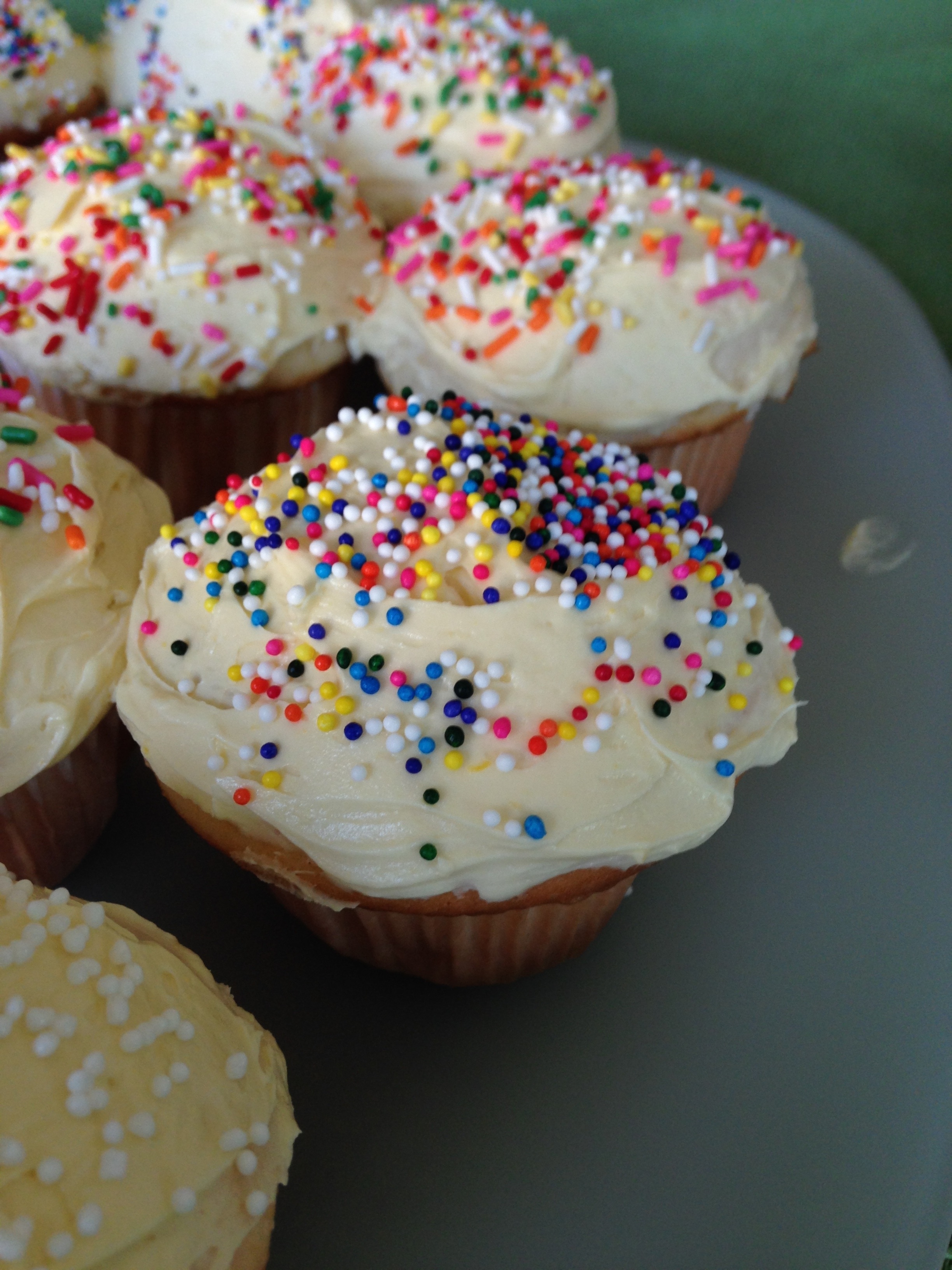 cupcakes topped with white cream and sprinkles