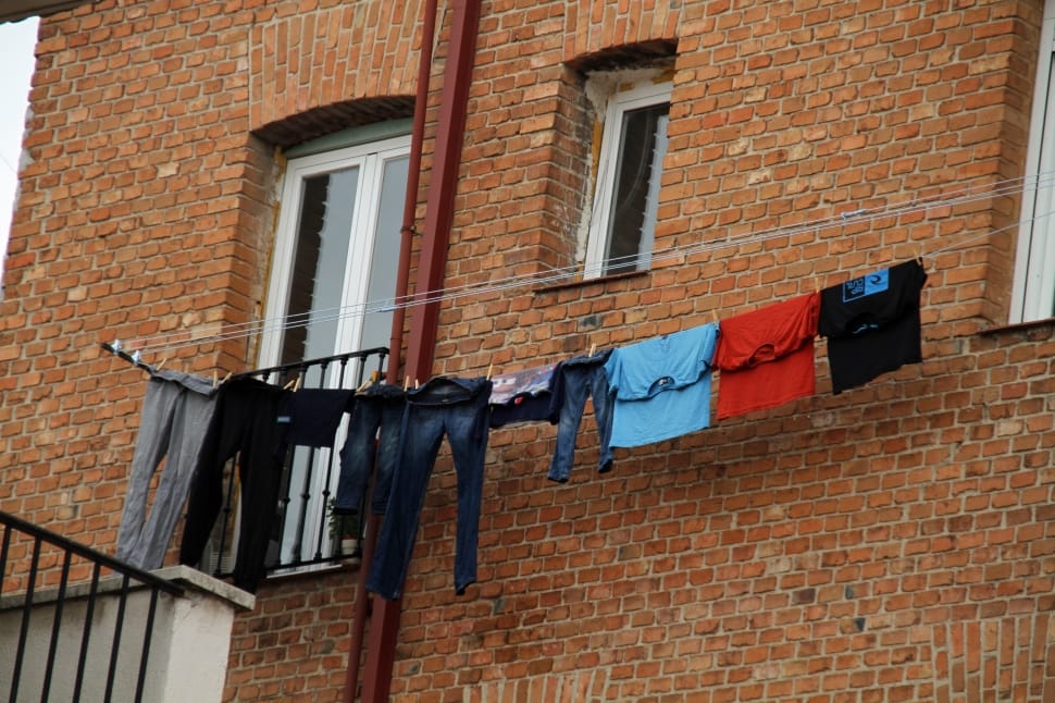 pants and clothes hanged on string beside brown high rise bricked made building during daytime preview