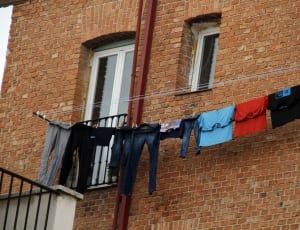 pants and clothes hanged on string beside brown high rise bricked made building during daytime thumbnail