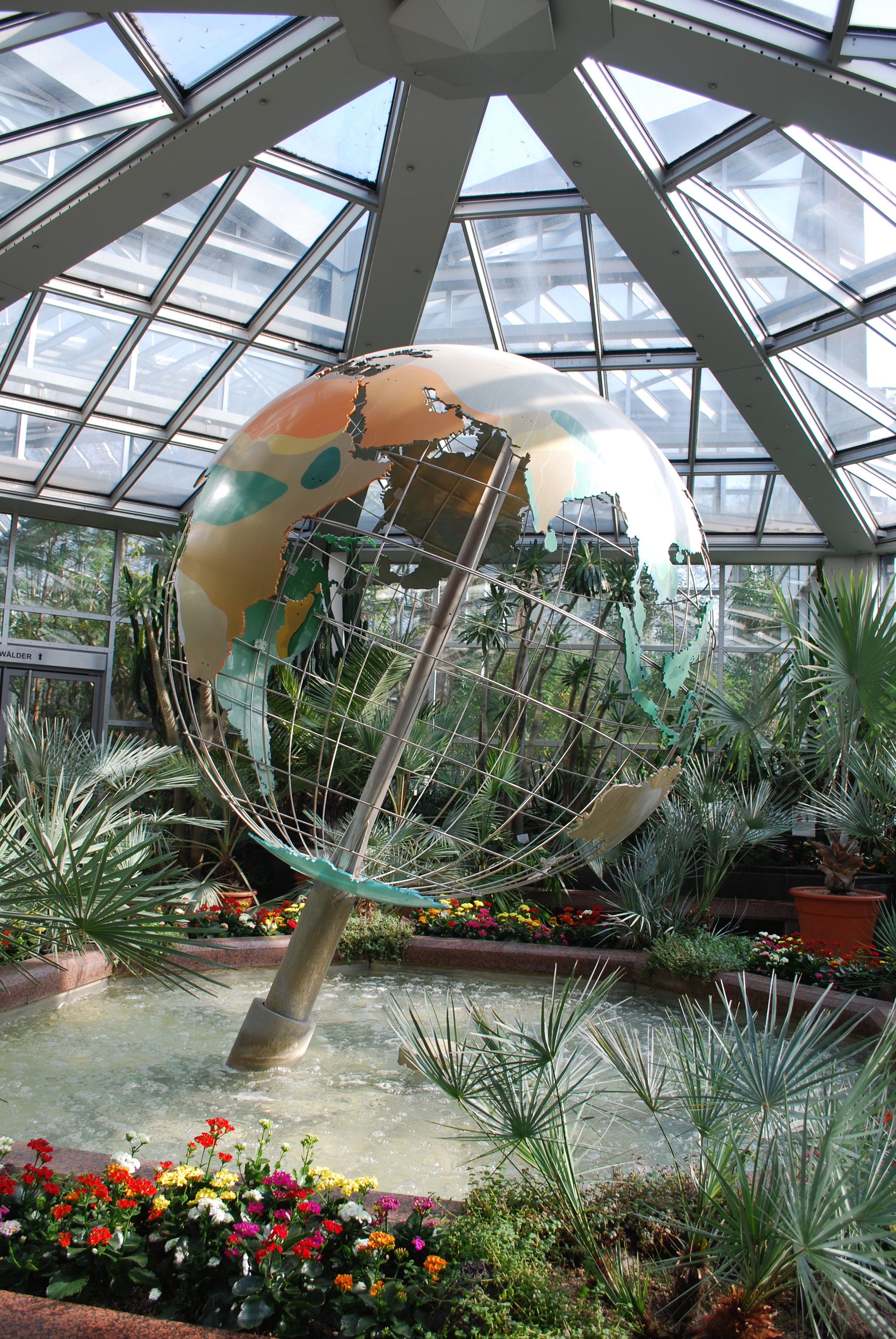 stainless steel, green and beige mesh globe on body of water near green leaf plants
