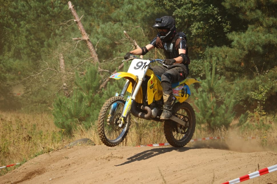 man riding yellow and white dirt bike performing motor cross during daytime preview