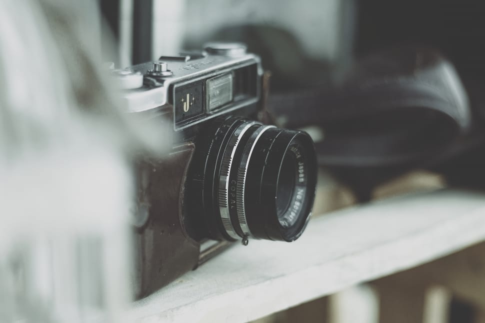 black and gray slr camera on white wooden fence preview
