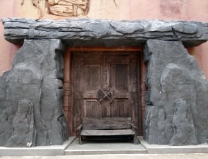brown wooden door between concrete stone hendge thumbnail