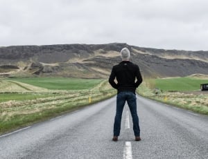 men's wearing black jacket standing on road way during daytime thumbnail