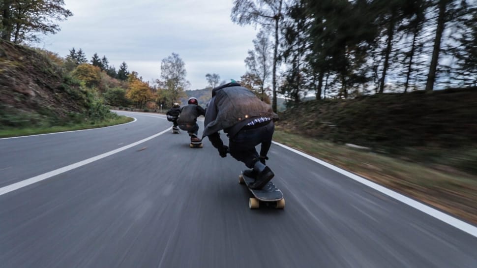 time lapse photography of 3 person doing downhill on using longboard at daytime preview
