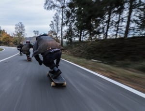 time lapse photography of 3 person doing downhill on using longboard at daytime thumbnail