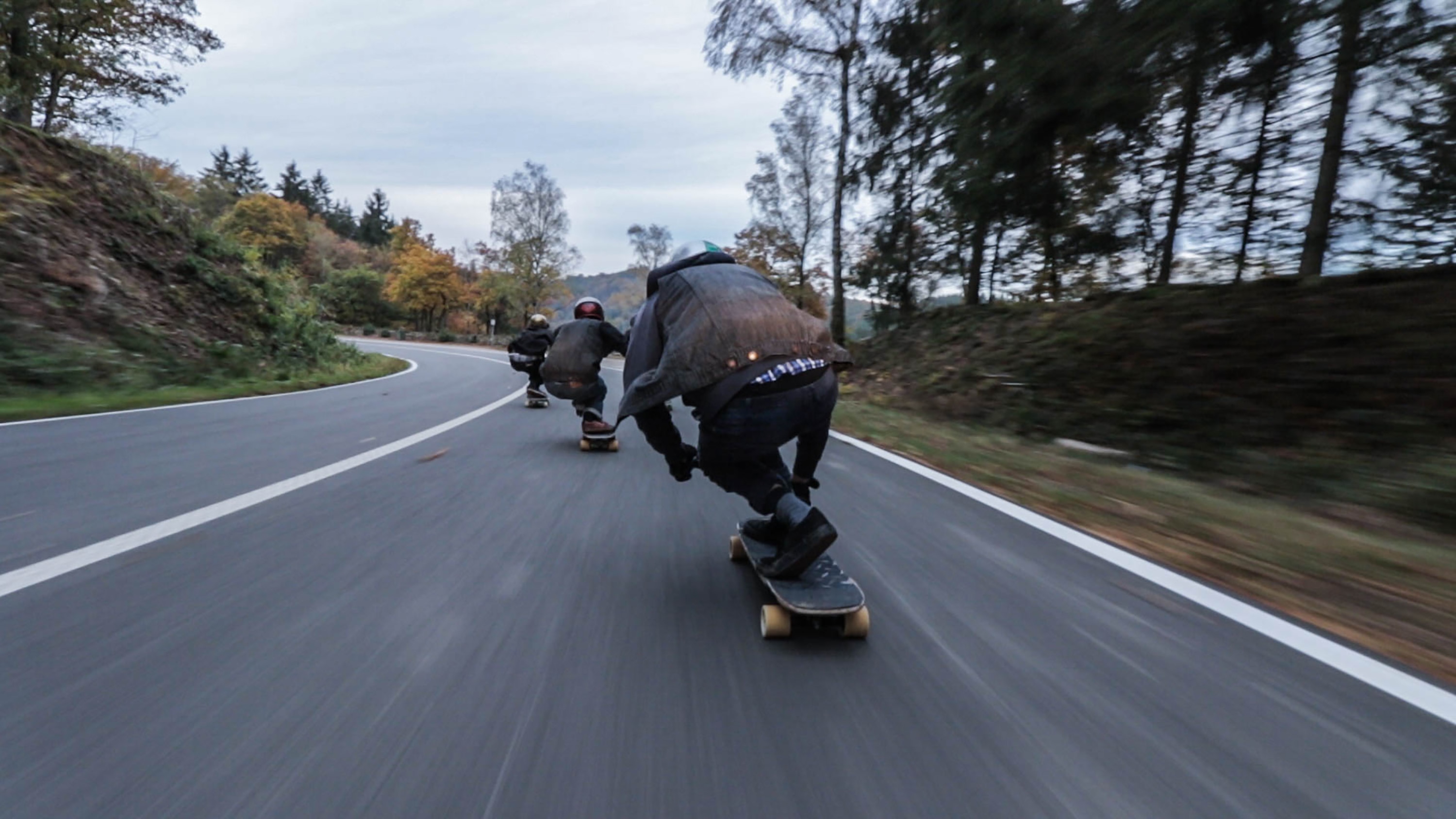time lapse photography of 3 person doing downhill on using longboard at daytime