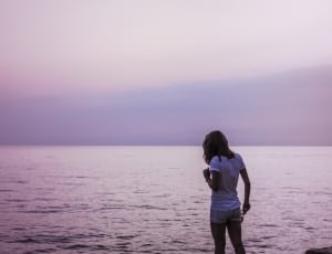 woman wearing white t shirt and shorts near sea during daytime thumbnail