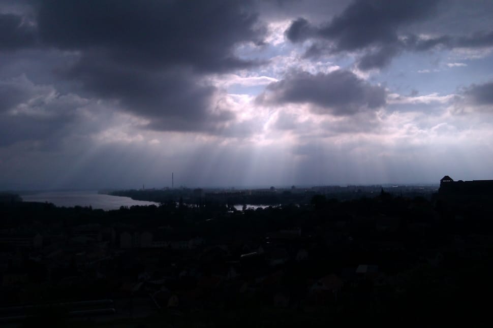 city under gray clouds with sun rays preview