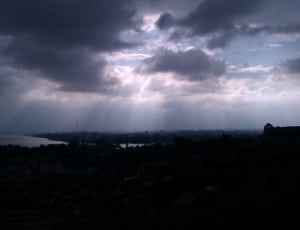 city under gray clouds with sun rays thumbnail