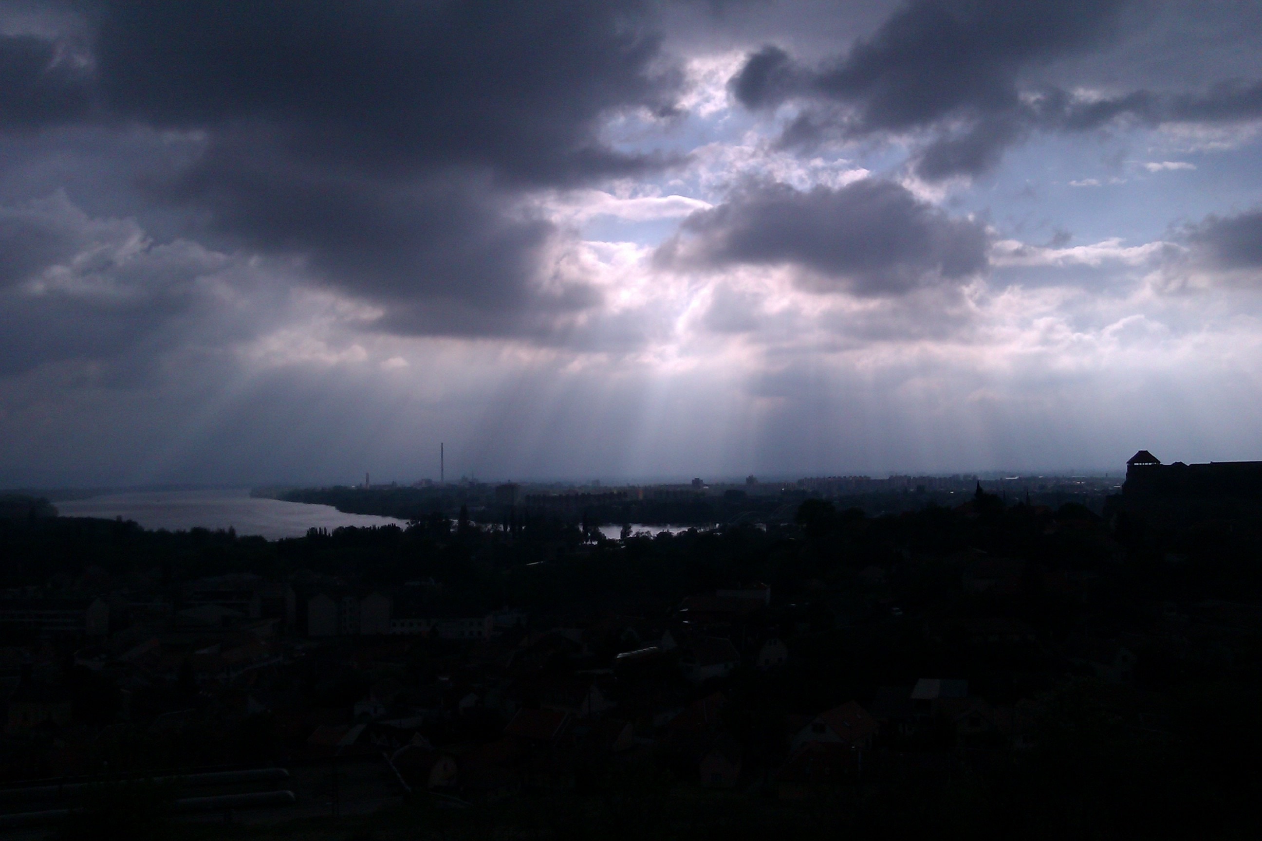 city under gray clouds with sun rays