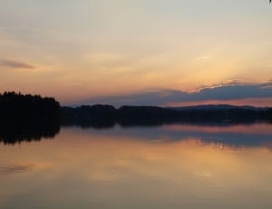 panoramic photo of land formation silhouette and body of water at daybreak thumbnail