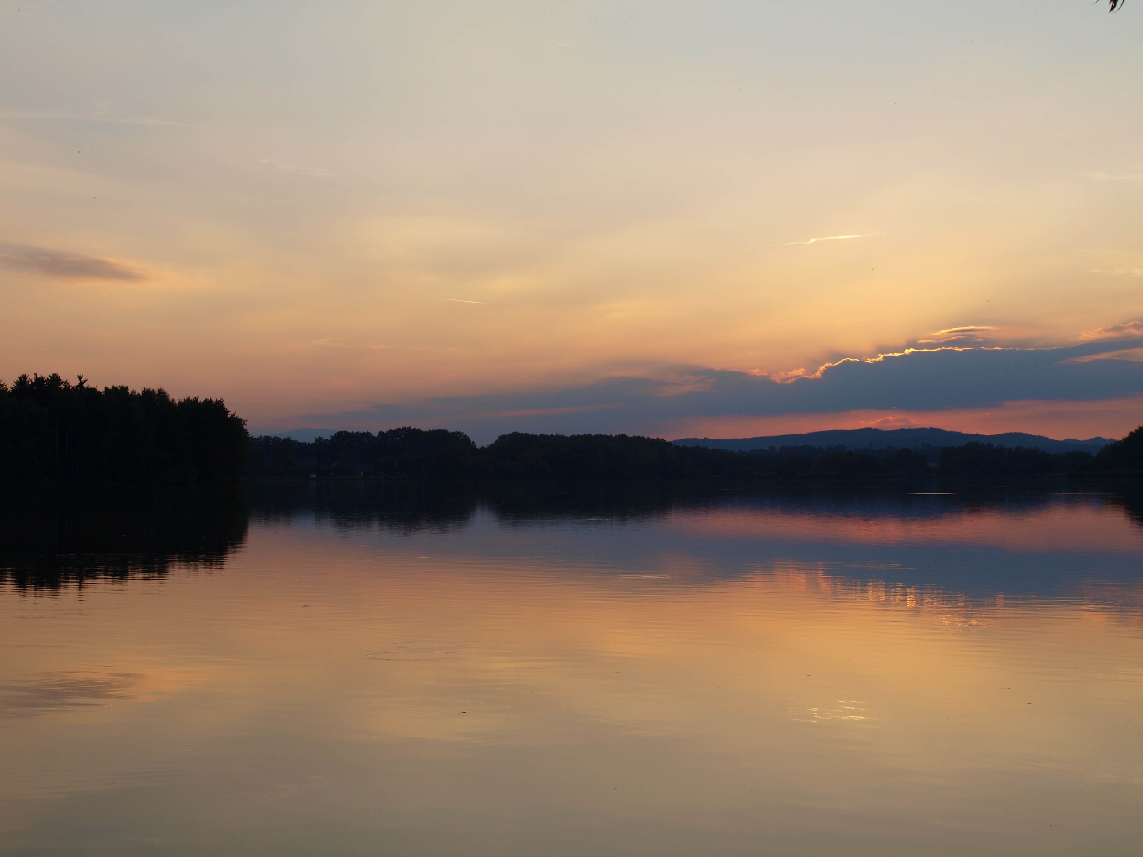 panoramic photo of land formation silhouette and body of water at daybreak