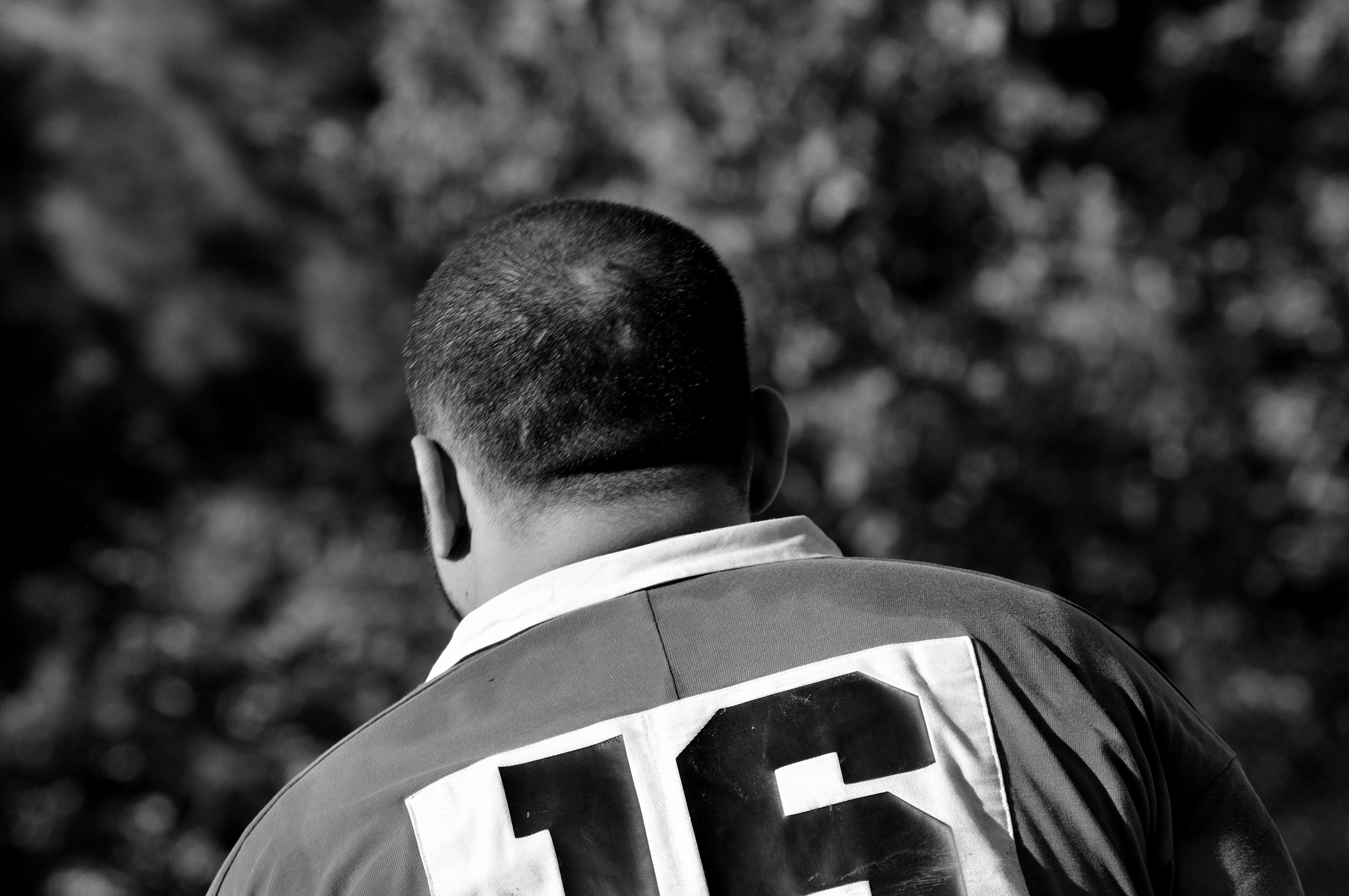 grayscale photo of man in number 16 jersey shirt facing backwards