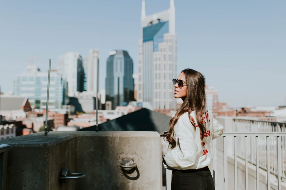 woman with white jacket next to tall buildings preview