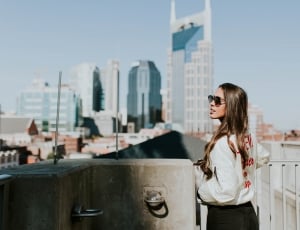 woman with white jacket next to tall buildings thumbnail