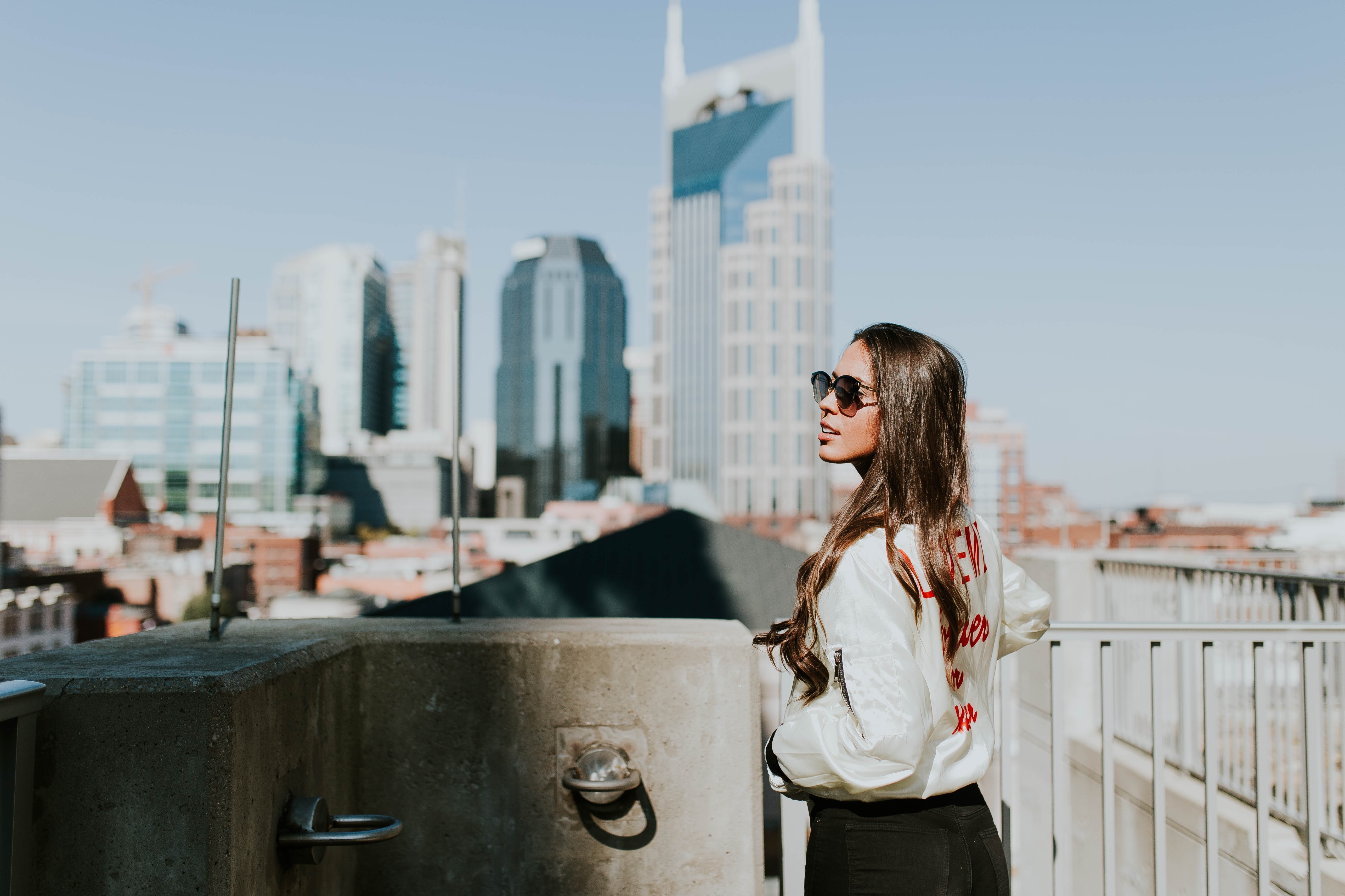 woman with white jacket next to tall buildings
